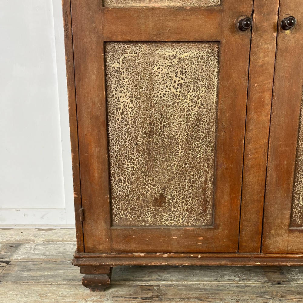 A nineteenth-century two-door pine cupboard featuring distressed crackle-glaze panel doors and a shaped cresting rail. View VII