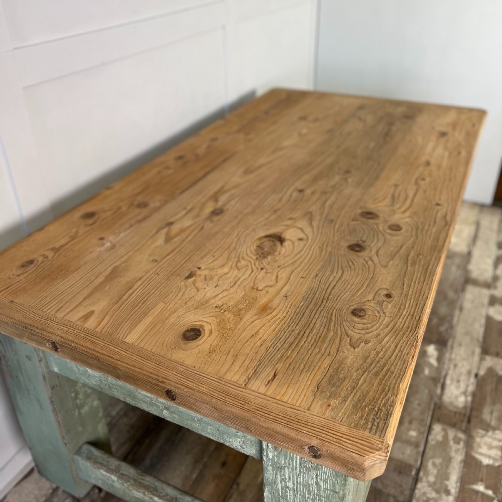 An early 20th-century pine work table featuring a natural scrubbed wood top and a distressed sage green painted frame supported by heavy cast iron castors. View VI