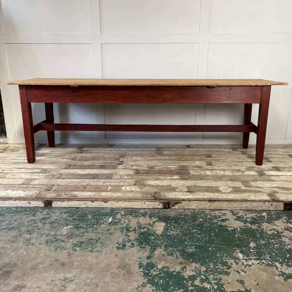 A long 19th-century Welsh pine refectory table featuring a natural timber plank top supported by a dark red painted frame with lower stretchers. View III
