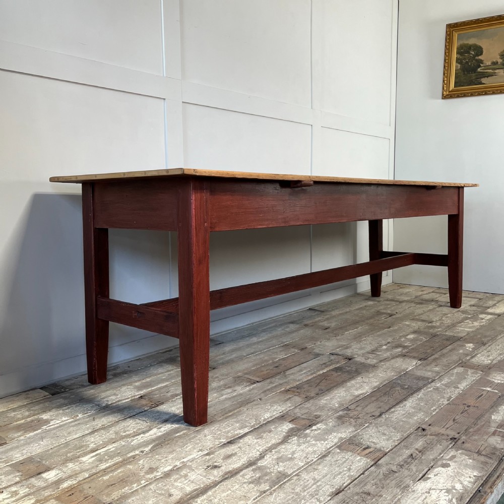 A long 19th-century Welsh pine refectory table featuring a natural timber plank top supported by a dark red painted frame with lower stretchers. View V