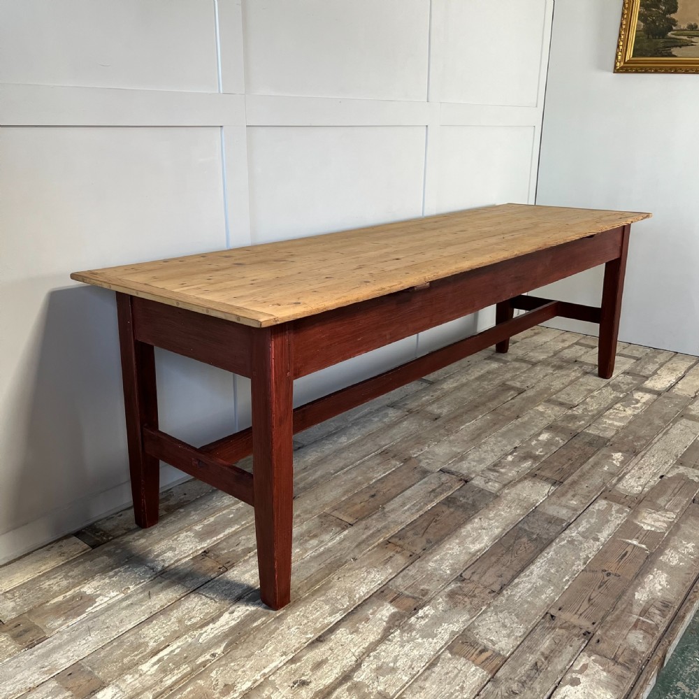 A long 19th-century Welsh pine refectory table featuring a natural timber plank top supported by a dark red painted frame with lower stretchers. View VI