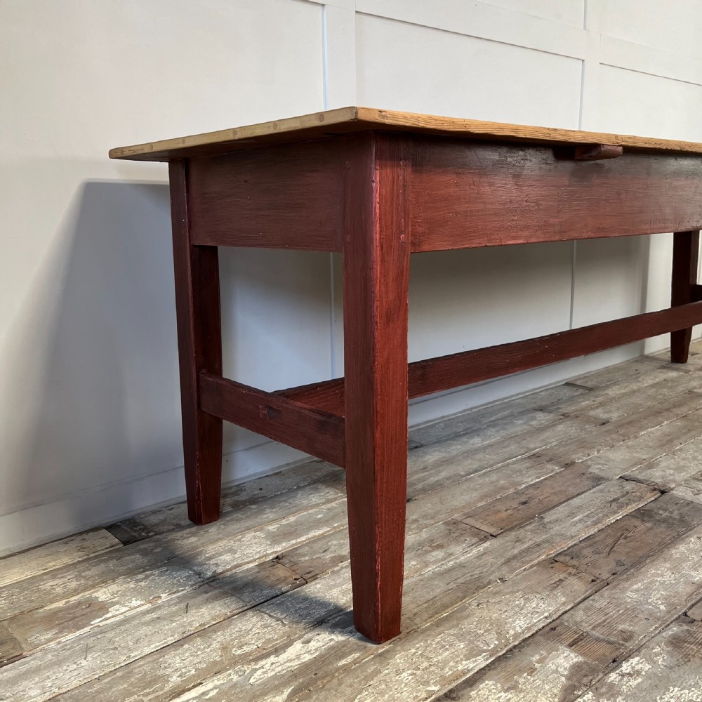 A long 19th-century Welsh pine refectory table featuring a natural timber plank top supported by a dark red painted frame with lower stretchers. View VII