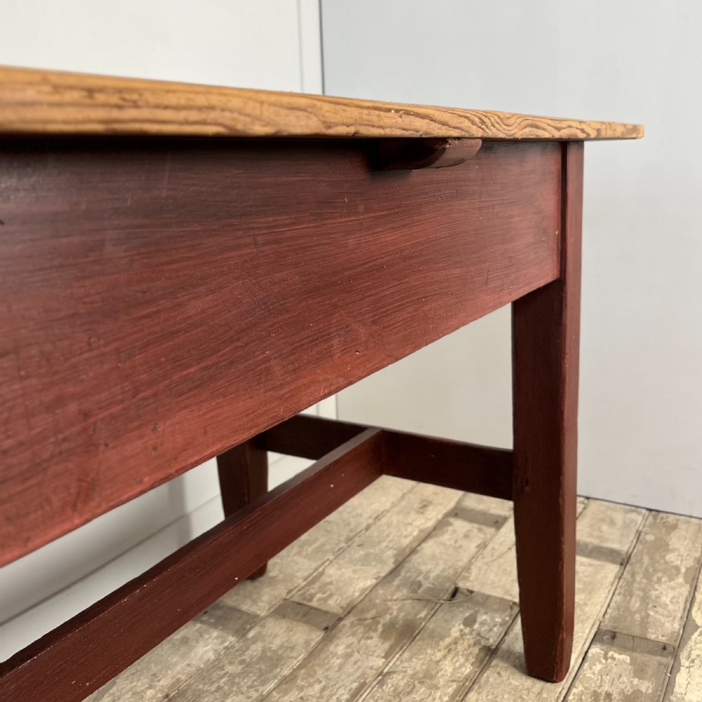 A long 19th-century Welsh pine refectory table featuring a natural timber plank top supported by a dark red painted frame with lower stretchers. View X