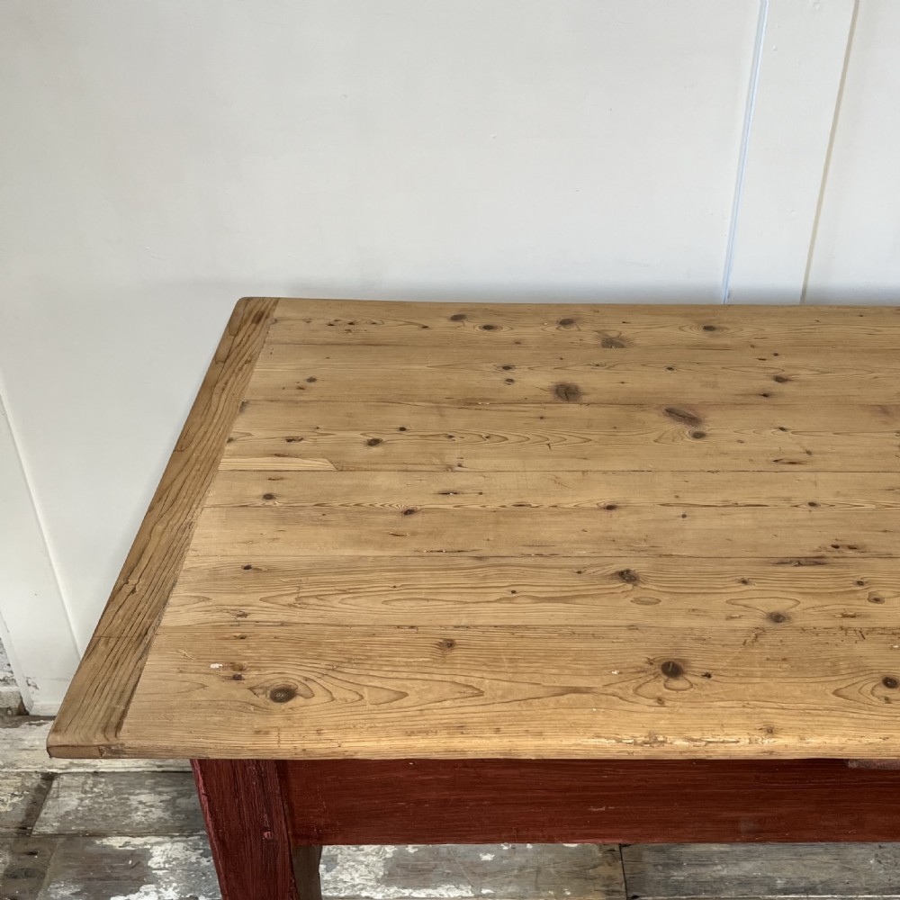 A long 19th-century Welsh pine refectory table featuring a natural timber plank top supported by a dark red painted frame with lower stretchers. View XIII