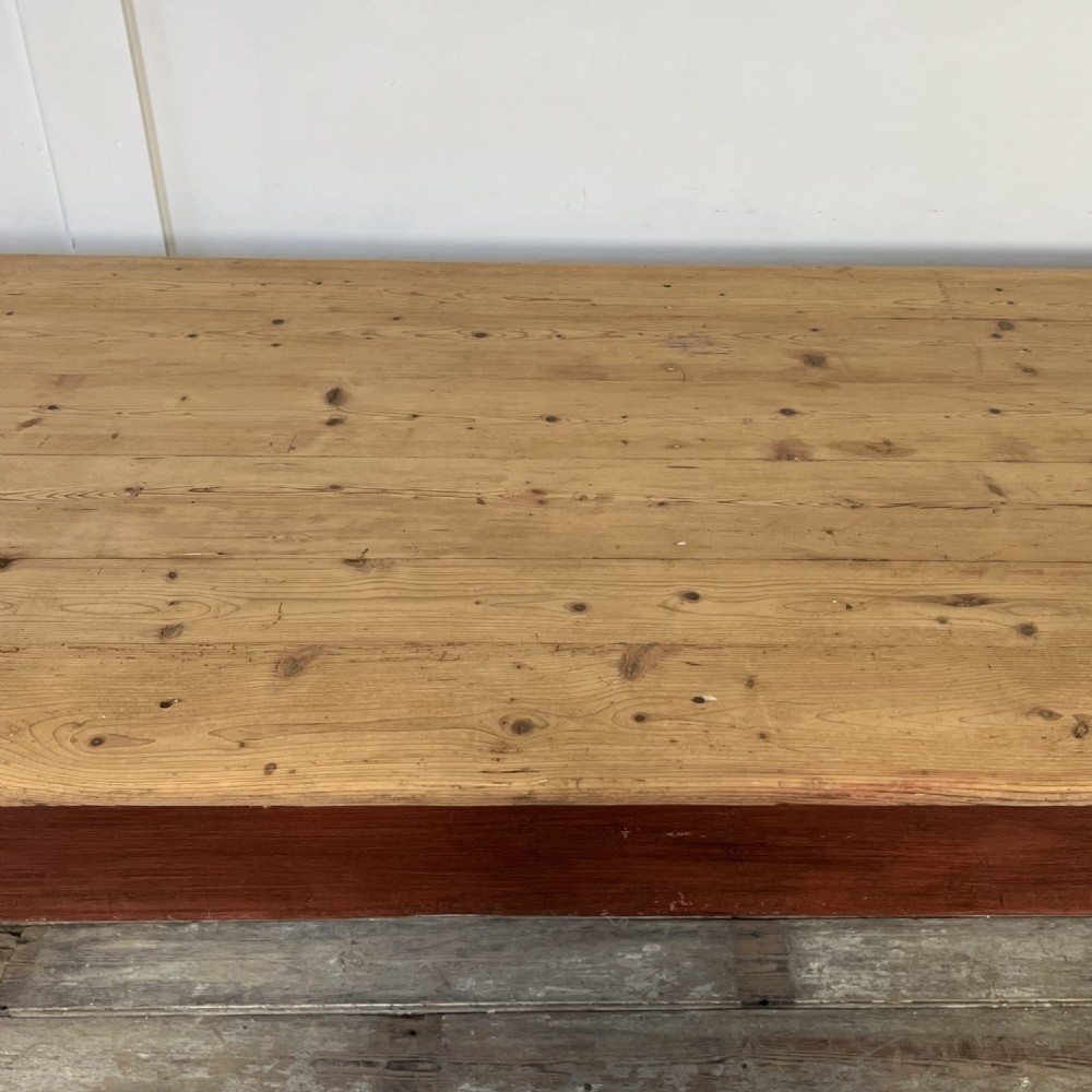 A long 19th-century Welsh pine refectory table featuring a natural timber plank top supported by a dark red painted frame with lower stretchers. View XIV