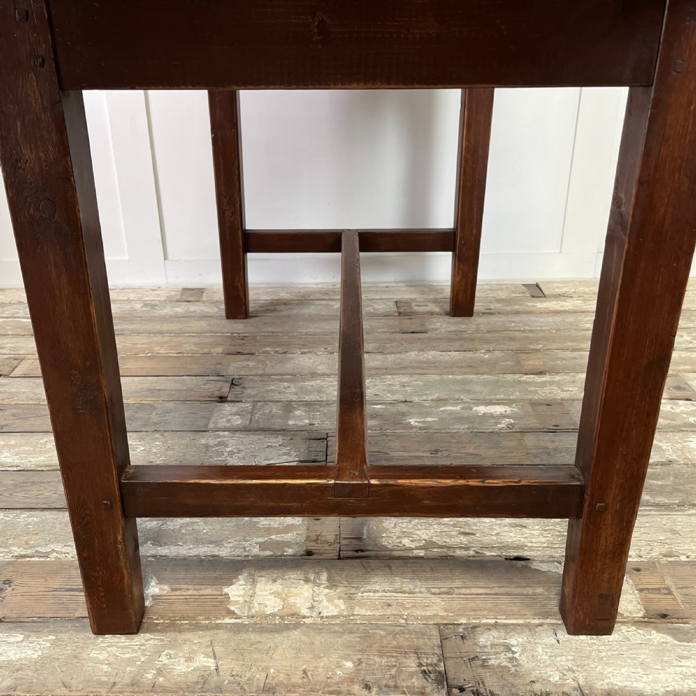 A 19th-century Welsh pine kitchen table featuring a light wood plank top supported by a dark stained wooden frame with square legs and a low stretcher. View V