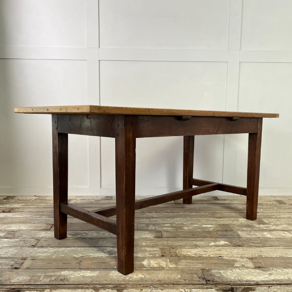A 19th-century Welsh pine kitchen table featuring a light wood plank top supported by a dark stained wooden frame with square legs and a low stretcher. View VI