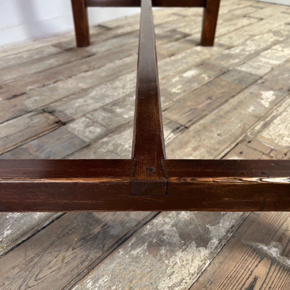 A 19th-century Welsh pine kitchen table featuring a light wood plank top supported by a dark stained wooden frame with square legs and a low stretcher. View VII