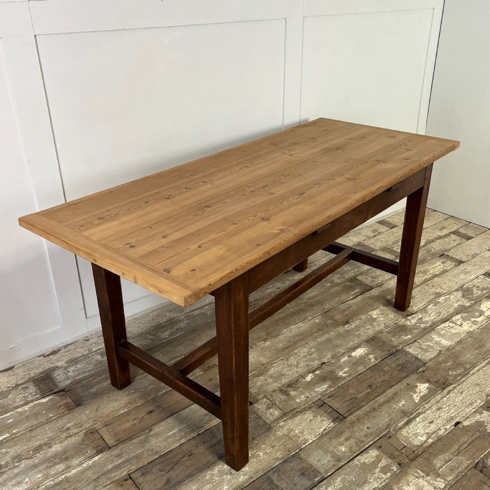 A 19th-century Welsh pine kitchen table featuring a light wood plank top supported by a dark stained wooden frame with square legs and a low stretcher. View IX
