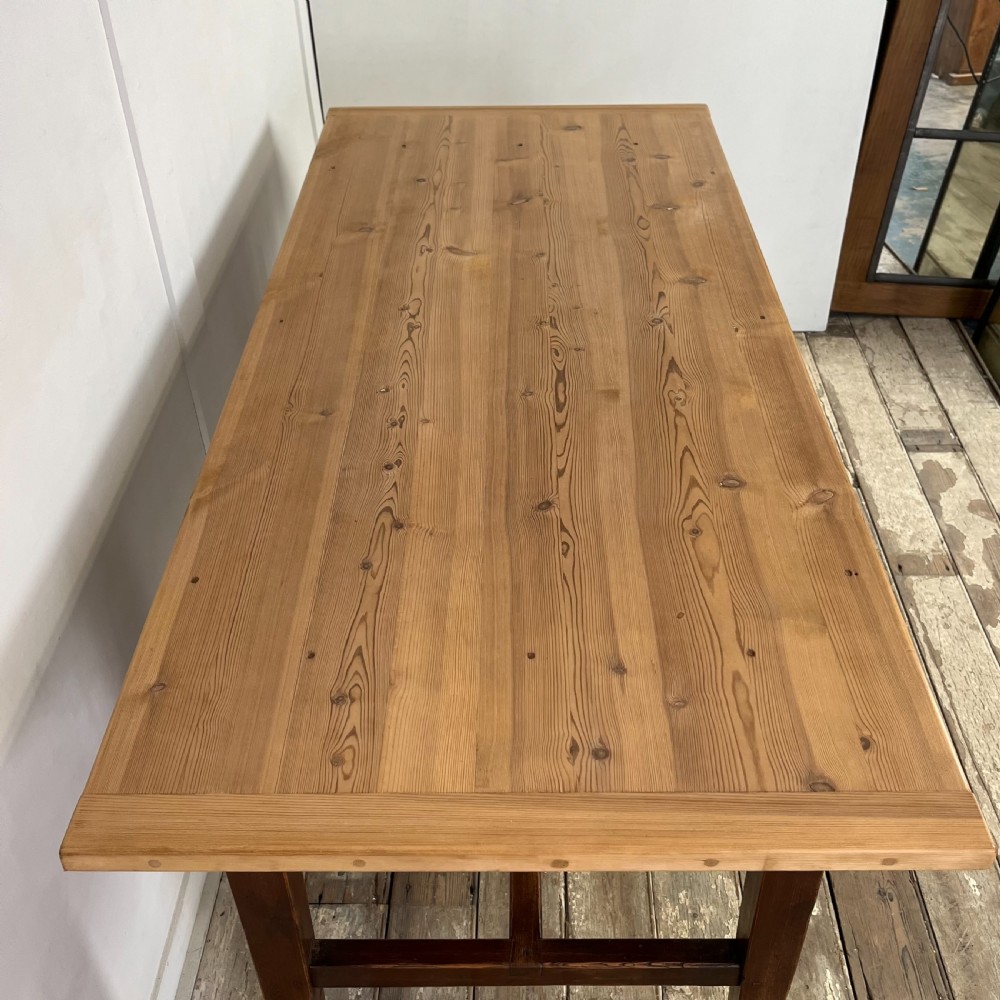 A 19th-century Welsh pine kitchen table featuring a light wood plank top supported by a dark stained wooden frame with square legs and a low stretcher. View X