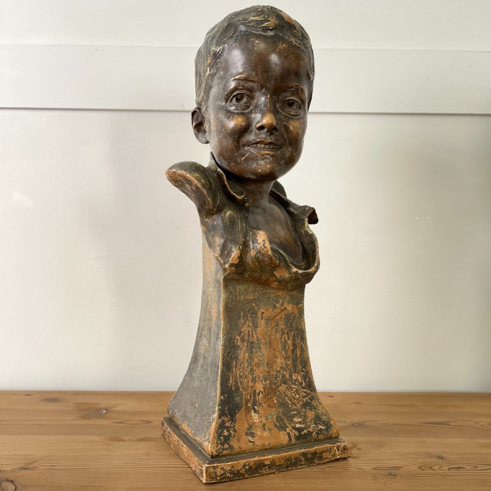 A pair of early 20th-century terracotta busts depicting a young boy and girl with aged bronze-effect finishes on integrated square pedestals. View II