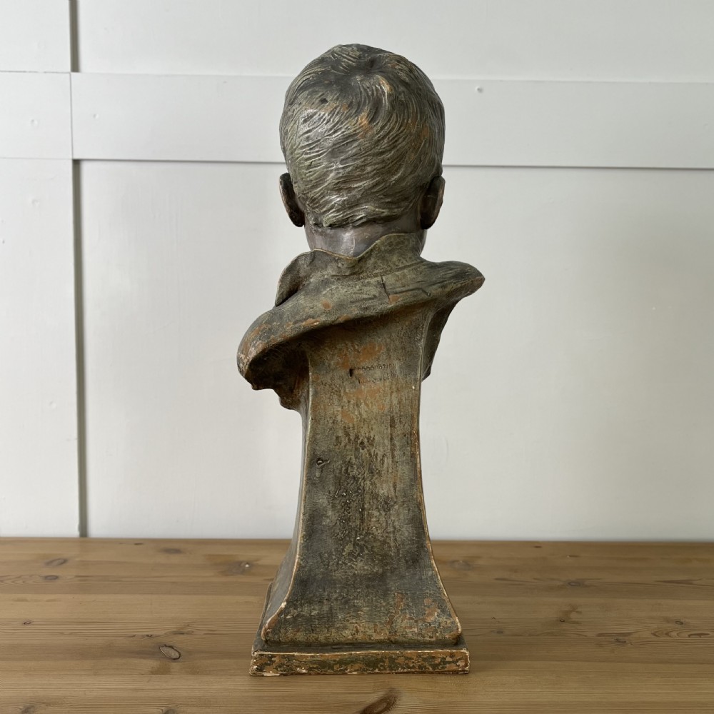 A pair of early 20th-century terracotta busts depicting a young boy and girl with aged bronze-effect finishes on integrated square pedestals. View VIII