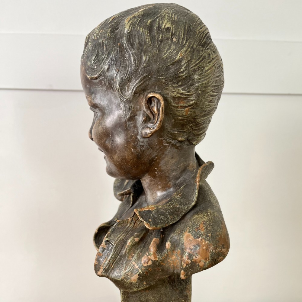 A pair of early 20th-century terracotta busts depicting a young boy and girl with aged bronze-effect finishes on integrated square pedestals. View IX