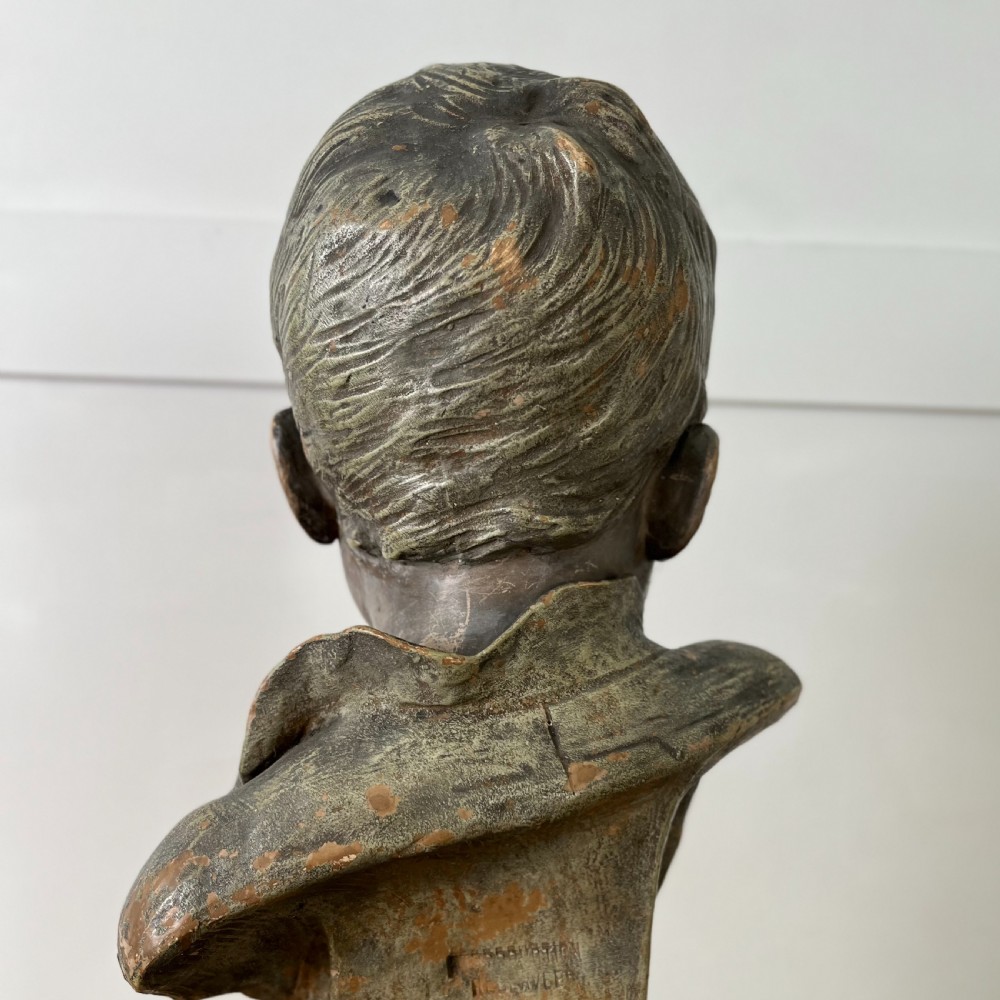 A pair of early 20th-century terracotta busts depicting a young boy and girl with aged bronze-effect finishes on integrated square pedestals. View X