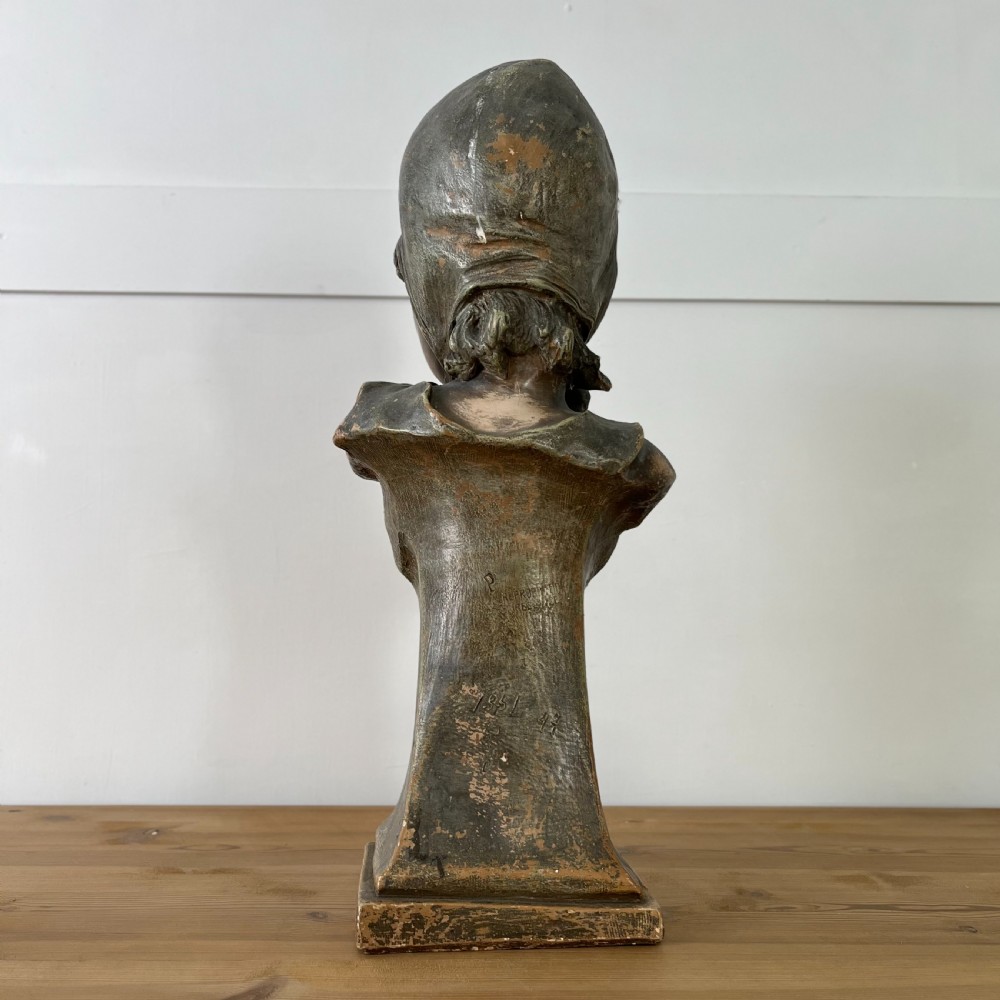 A pair of early 20th-century terracotta busts depicting a young boy and girl with aged bronze-effect finishes on integrated square pedestals. View XXII