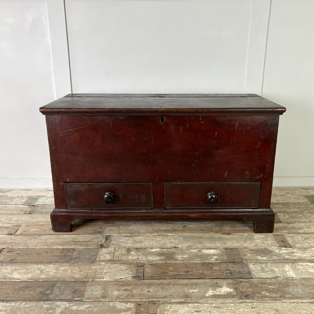 A dark red painted Georgian pine mule chest featuring a hinged top lid above two lower drawers with turned wooden knobs. View II