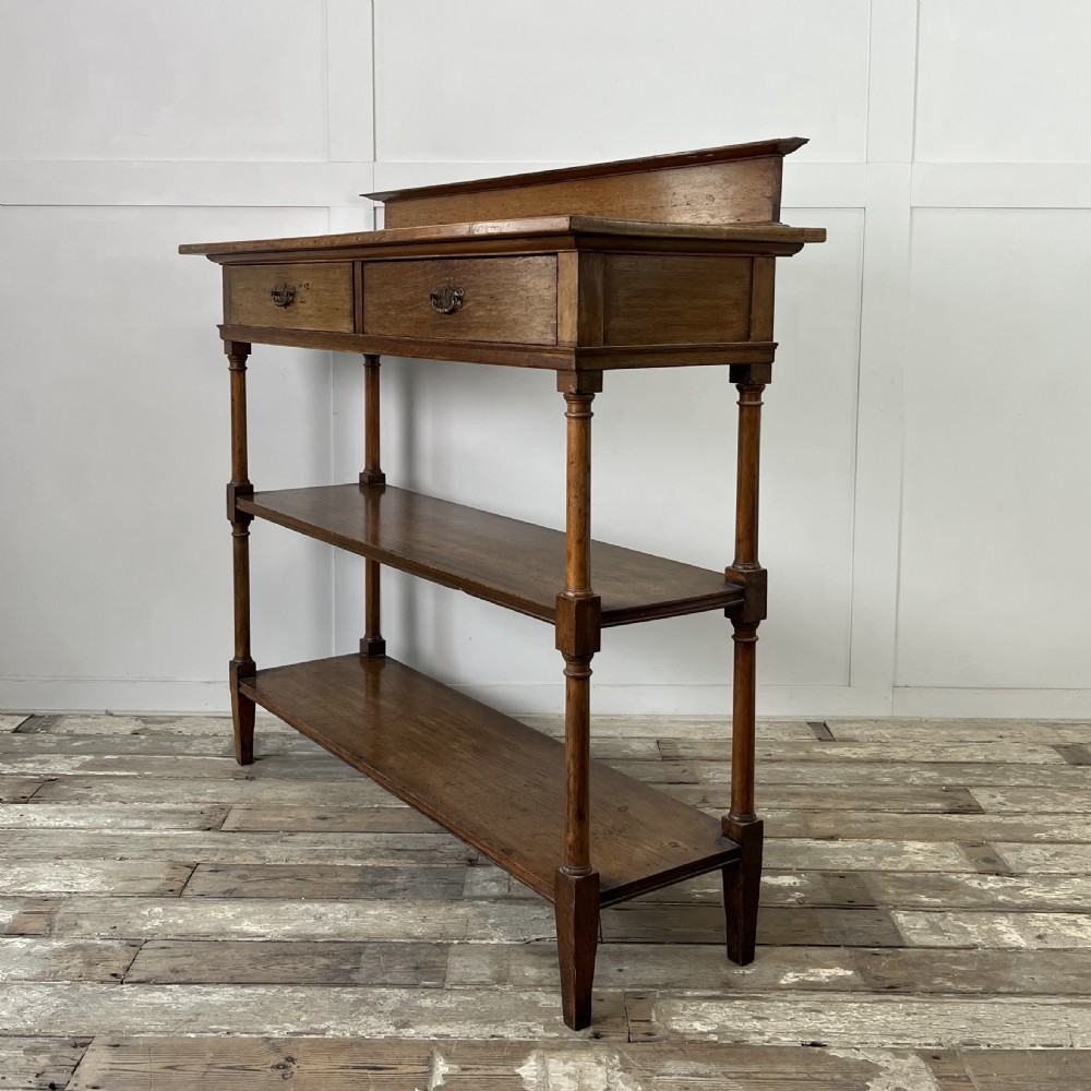 A pair of Victorian oak serving tables featuring tiered shelves, turned upright supports, and two frieze drawers with brass handles. View X