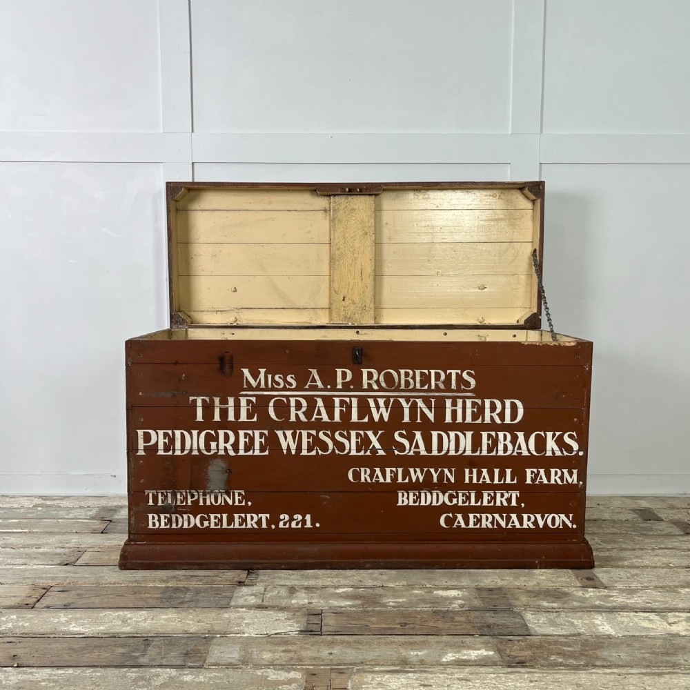 A rectangular reddish-brown painted pine storage chest featuring white hand-painted agricultural typography on the front panel. View III