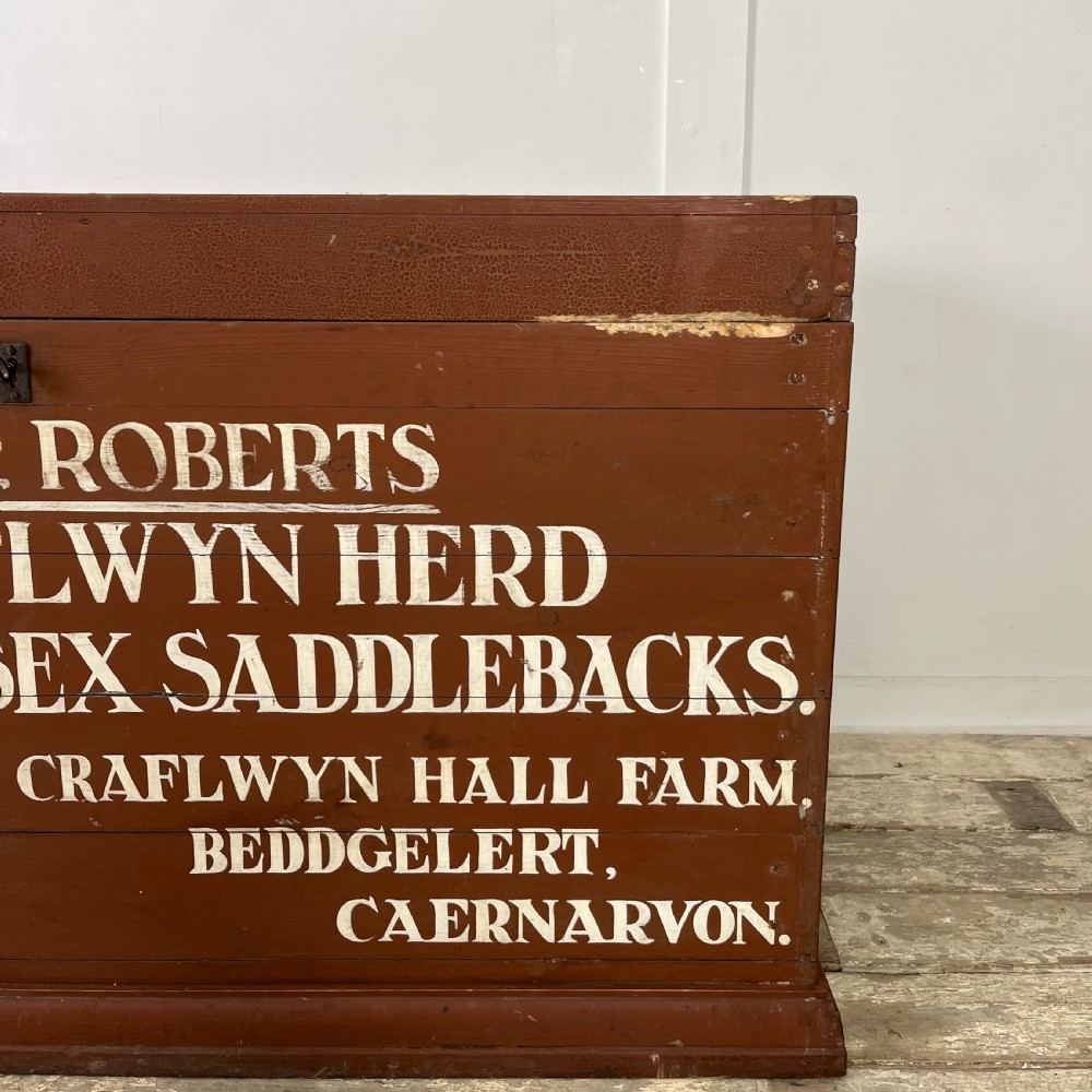 A rectangular reddish-brown painted pine storage chest featuring white hand-painted agricultural typography on the front panel. View V