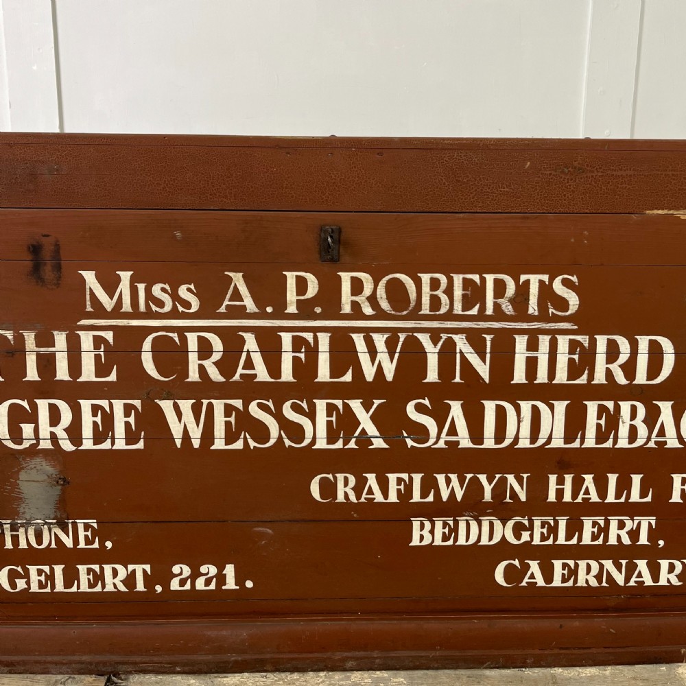 A rectangular reddish-brown painted pine storage chest featuring white hand-painted agricultural typography on the front panel. View VI