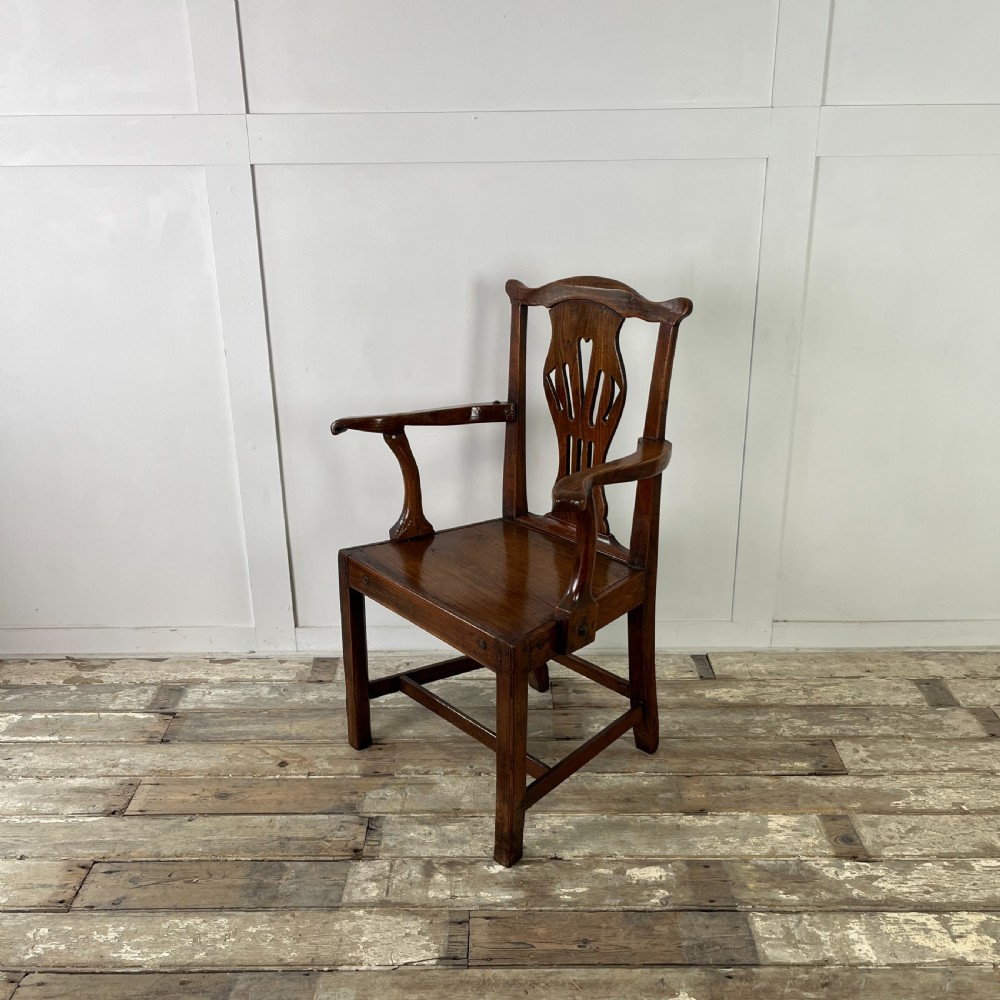 A dark brown early nineteenth-century elm armchair featuring a shaped top rail, a pierced vertical back splat, curved armrests, a solid timber seat, and straight legs joined by stretchers. View III