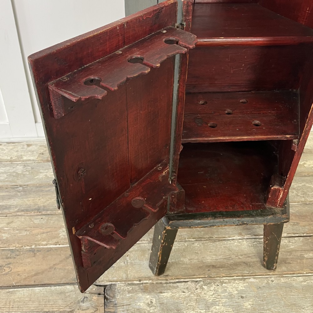 A 19th-century European folk art childs high chair featuring a dark painted enclosed cupboard base and a crimson shaped backrest decorated with hand-painted floral motifs. View III