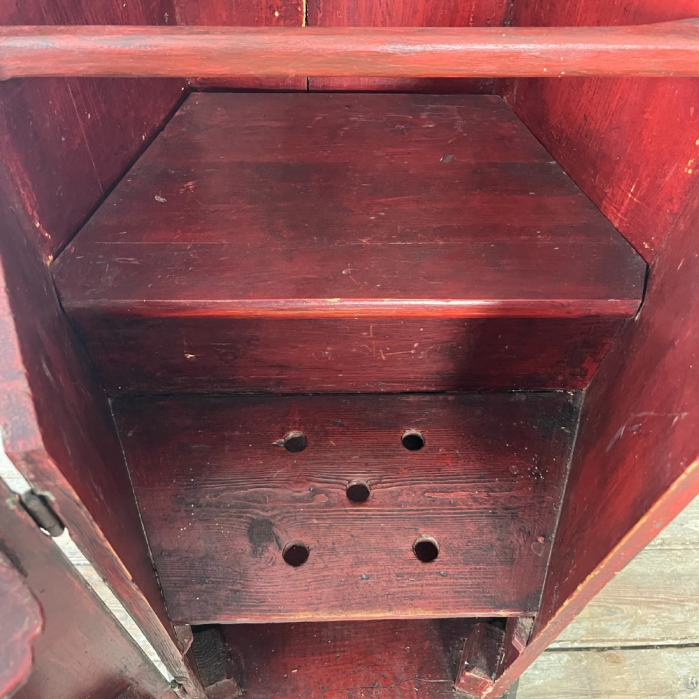 A 19th-century European folk art childs high chair featuring a dark painted enclosed cupboard base and a crimson shaped backrest decorated with hand-painted floral motifs. View VIII