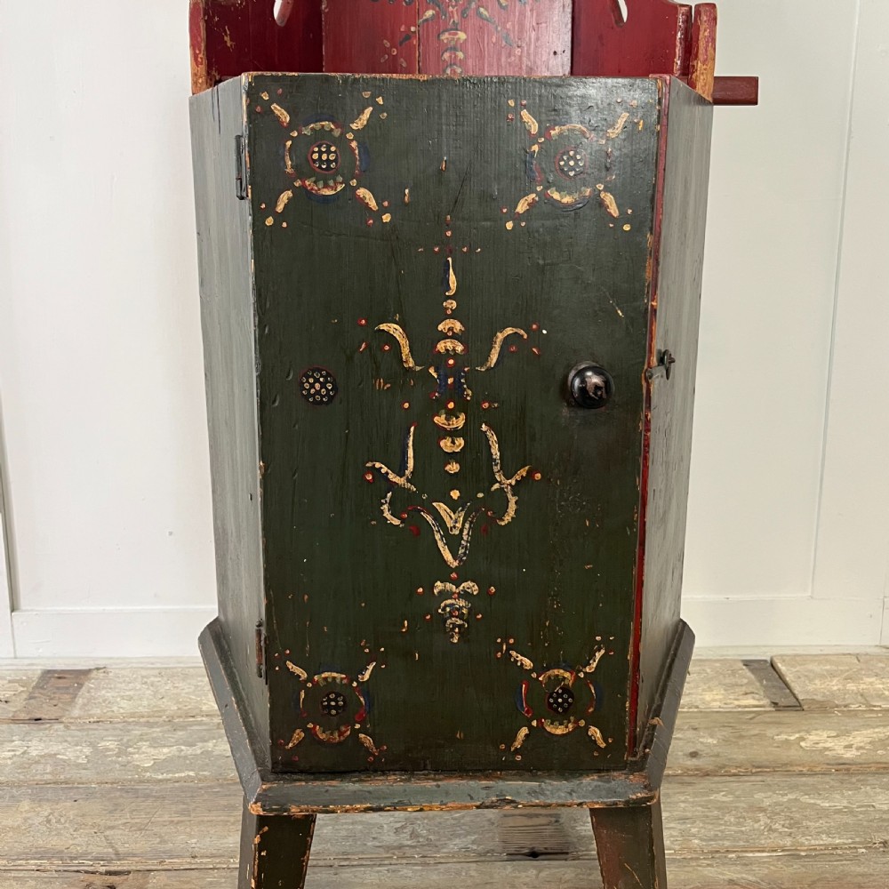 A 19th-century European folk art childs high chair featuring a dark painted enclosed cupboard base and a crimson shaped backrest decorated with hand-painted floral motifs. View XIV