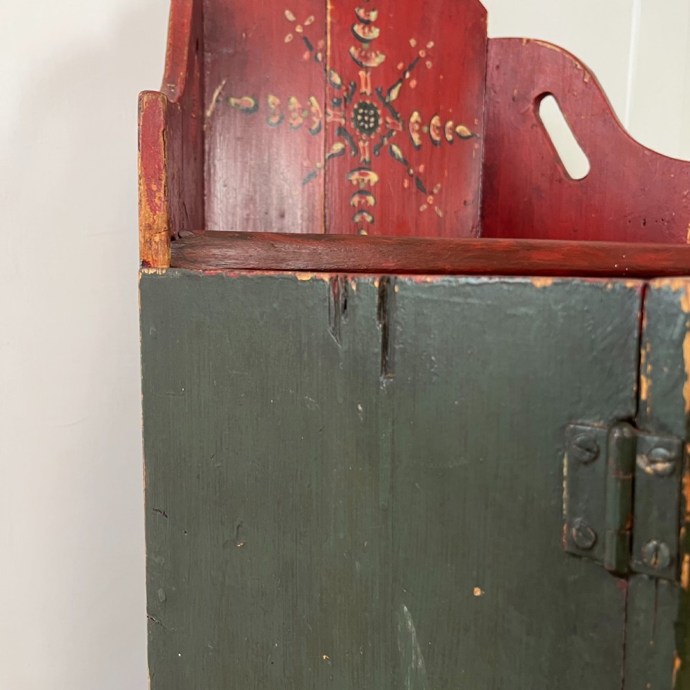 A 19th-century European folk art childs high chair featuring a dark painted enclosed cupboard base and a crimson shaped backrest decorated with hand-painted floral motifs. View XVI