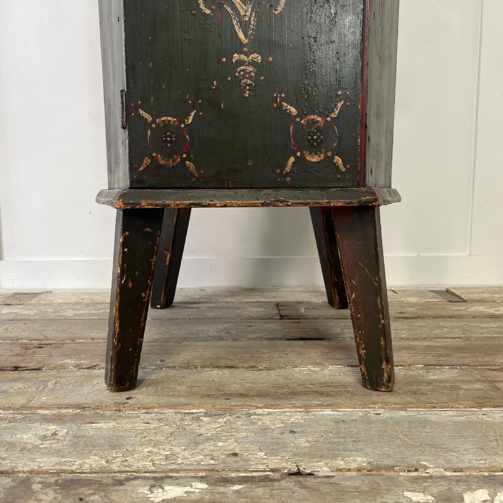 A 19th-century European folk art childs high chair featuring a dark painted enclosed cupboard base and a crimson shaped backrest decorated with hand-painted floral motifs. View XVIII