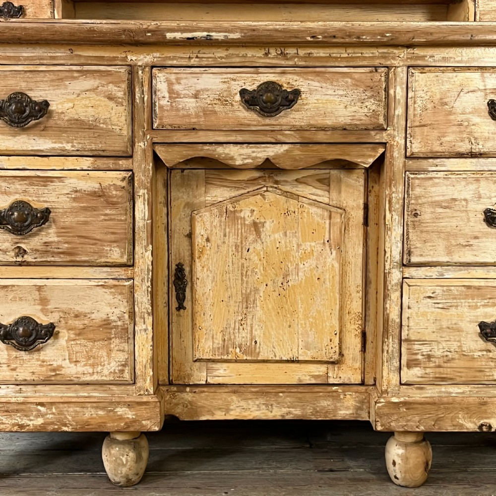 Victorian painted pine dresser with a shaped architectural backboard, multiple drawers, central cupboard, and bun feet in a distressed finish. View V