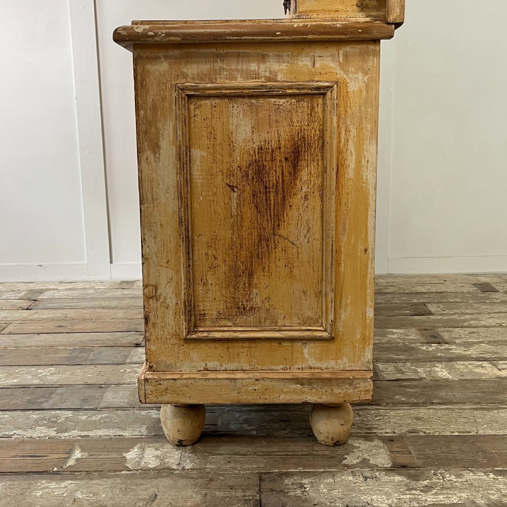 Victorian painted pine dresser with a shaped architectural backboard, multiple drawers, central cupboard, and bun feet in a distressed finish. View X