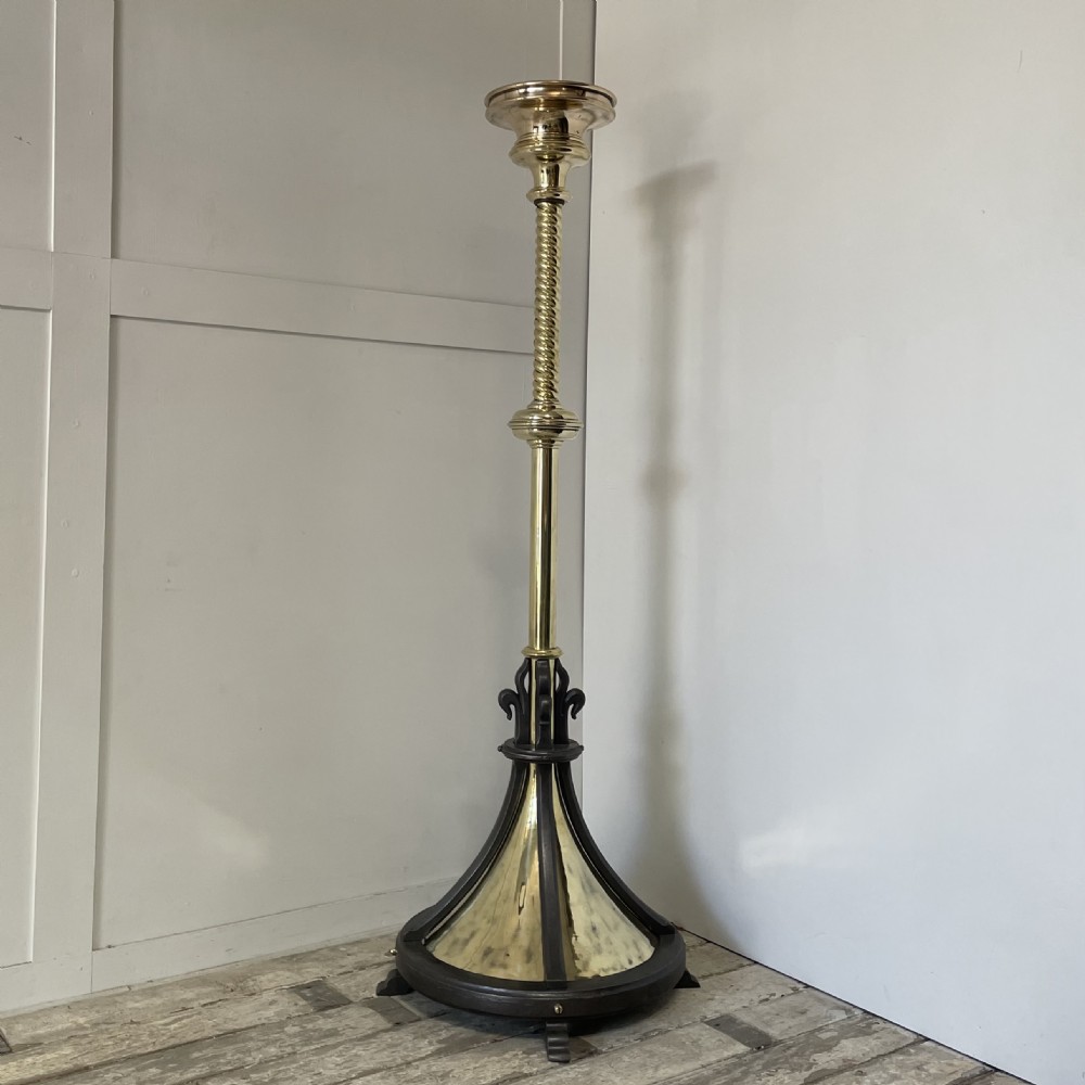A tall 19th-century Gothic Revival floor-standing church candlestick with a spiral-twist brass column and a dark metal flared base.