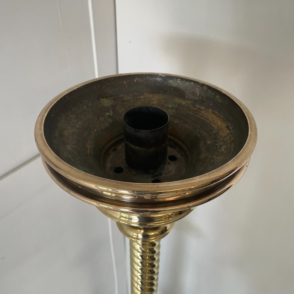 A tall 19th-century Gothic Revival floor-standing church candlestick with a spiral-twist brass column and a dark metal flared base. View X
