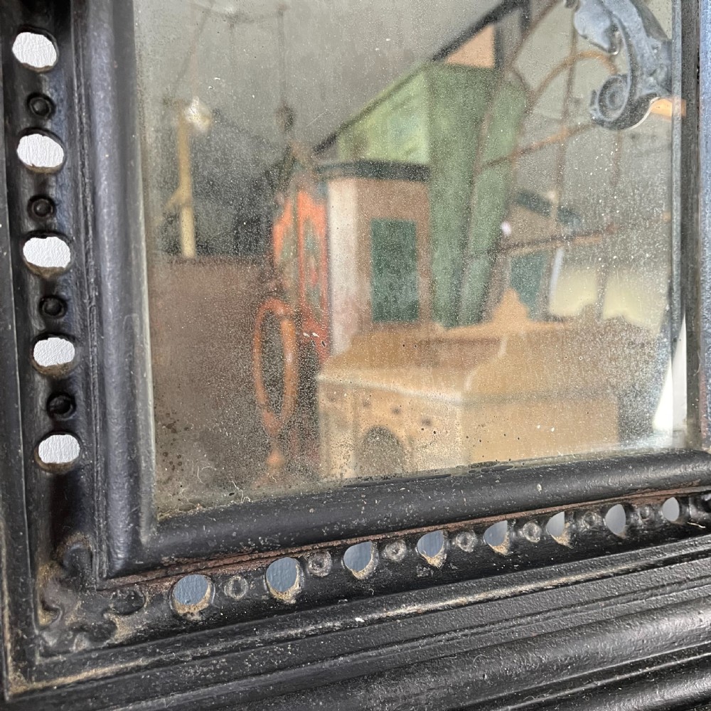 A tall black cast iron Victorian hall stand featuring an integrated central mirror, branching coat hooks, scrollwork tracery, and an umbrella drip tray at the base. View VII