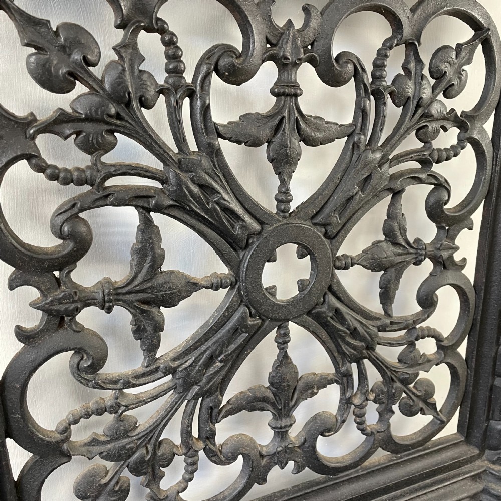 A tall black cast iron Victorian hall stand featuring an integrated central mirror, branching coat hooks, scrollwork tracery, and an umbrella drip tray at the base. View VIII