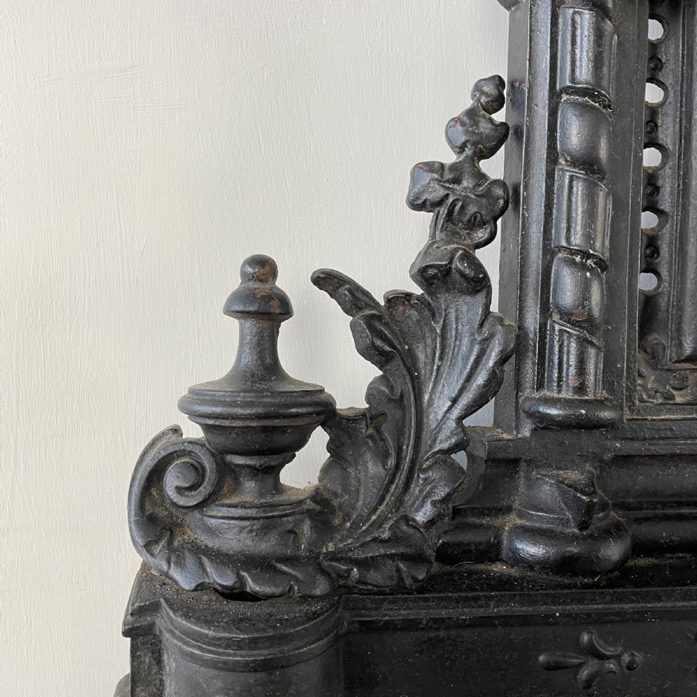 A tall black cast iron Victorian hall stand featuring an integrated central mirror, branching coat hooks, scrollwork tracery, and an umbrella drip tray at the base. View IX