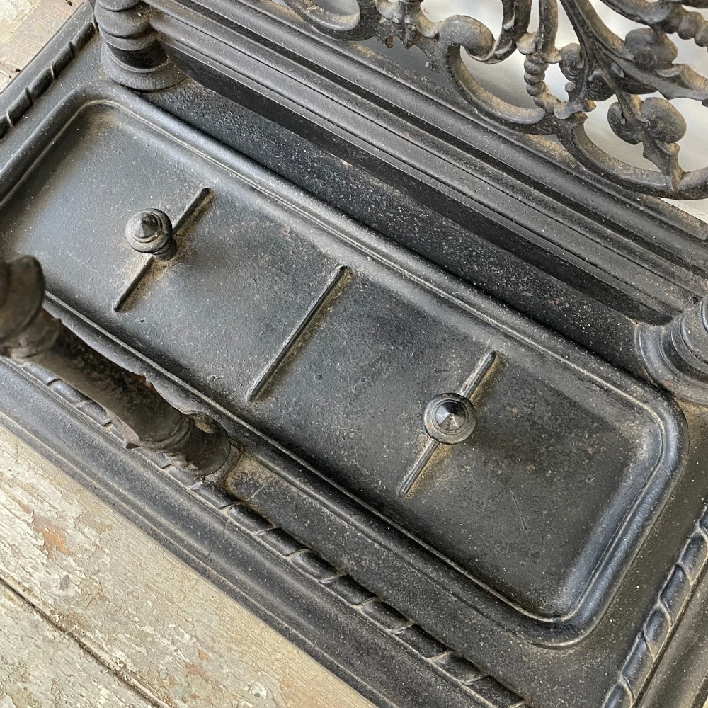 A tall black cast iron Victorian hall stand featuring an integrated central mirror, branching coat hooks, scrollwork tracery, and an umbrella drip tray at the base. View XIII