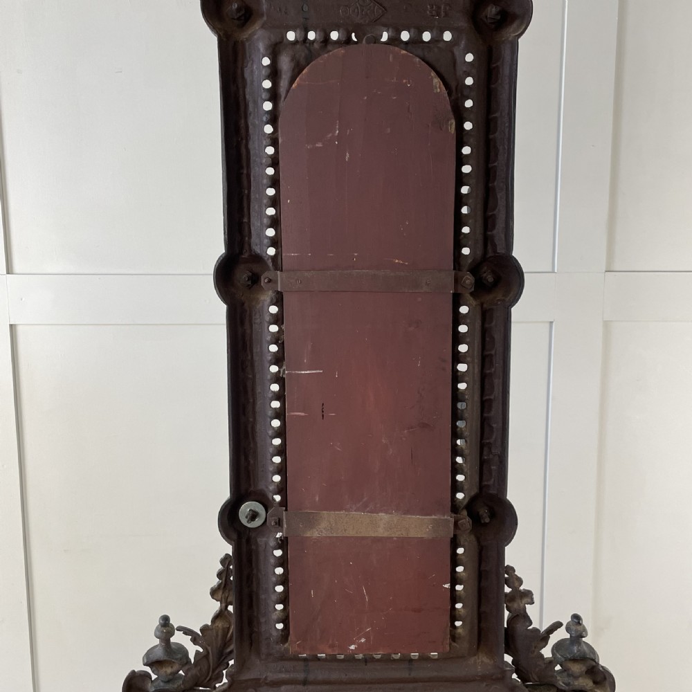 A tall black cast iron Victorian hall stand featuring an integrated central mirror, branching coat hooks, scrollwork tracery, and an umbrella drip tray at the base. View XX