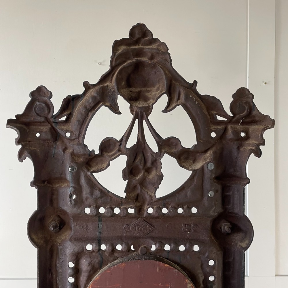 A tall black cast iron Victorian hall stand featuring an integrated central mirror, branching coat hooks, scrollwork tracery, and an umbrella drip tray at the base. View XXII