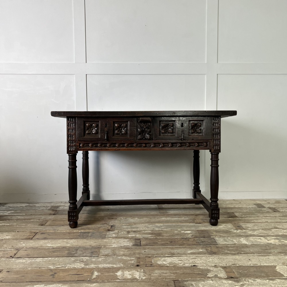 An early nineteenth-century Spanish dark walnut console table featuring carved panel drawers, turned legs, and an H-stretcher.