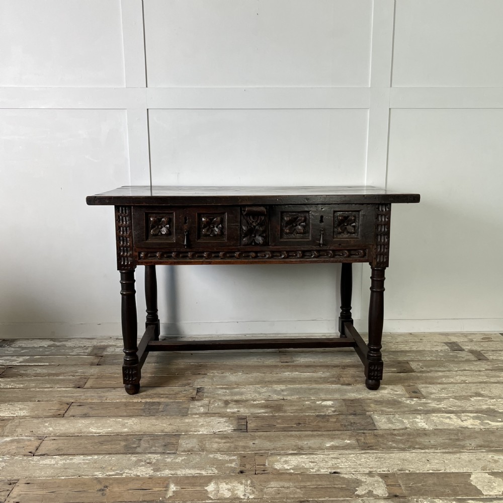 An early nineteenth-century Spanish dark walnut console table featuring carved panel drawers, turned legs, and an H-stretcher. View II
