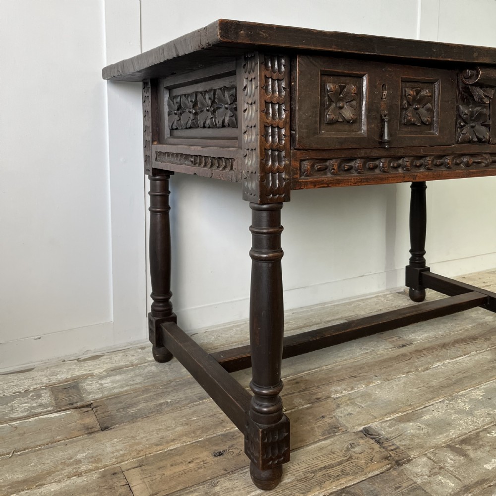 An early nineteenth-century Spanish dark walnut console table featuring carved panel drawers, turned legs, and an H-stretcher. View VI
