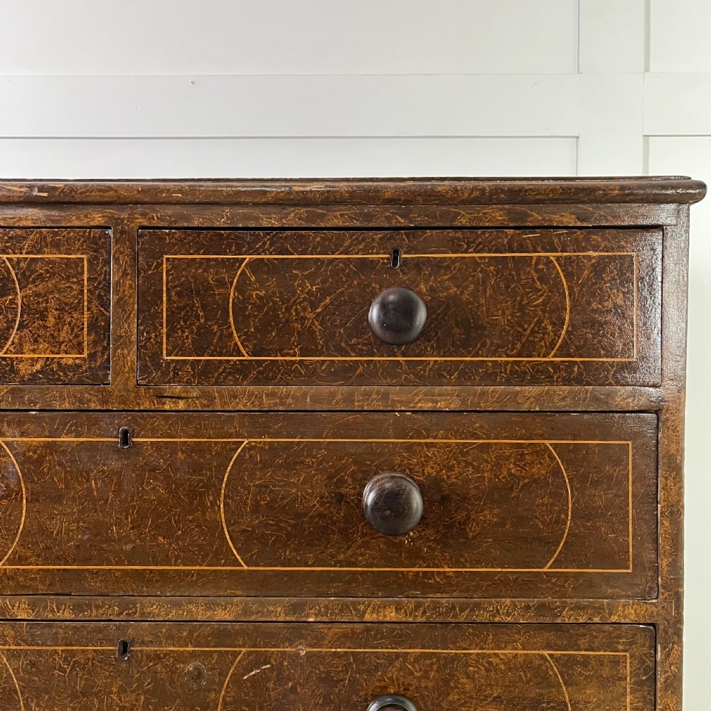 A nineteenth-century scumble-painted pine chest of drawers with decorative faux inlay lines, dark turned handles, and ball feet. View III