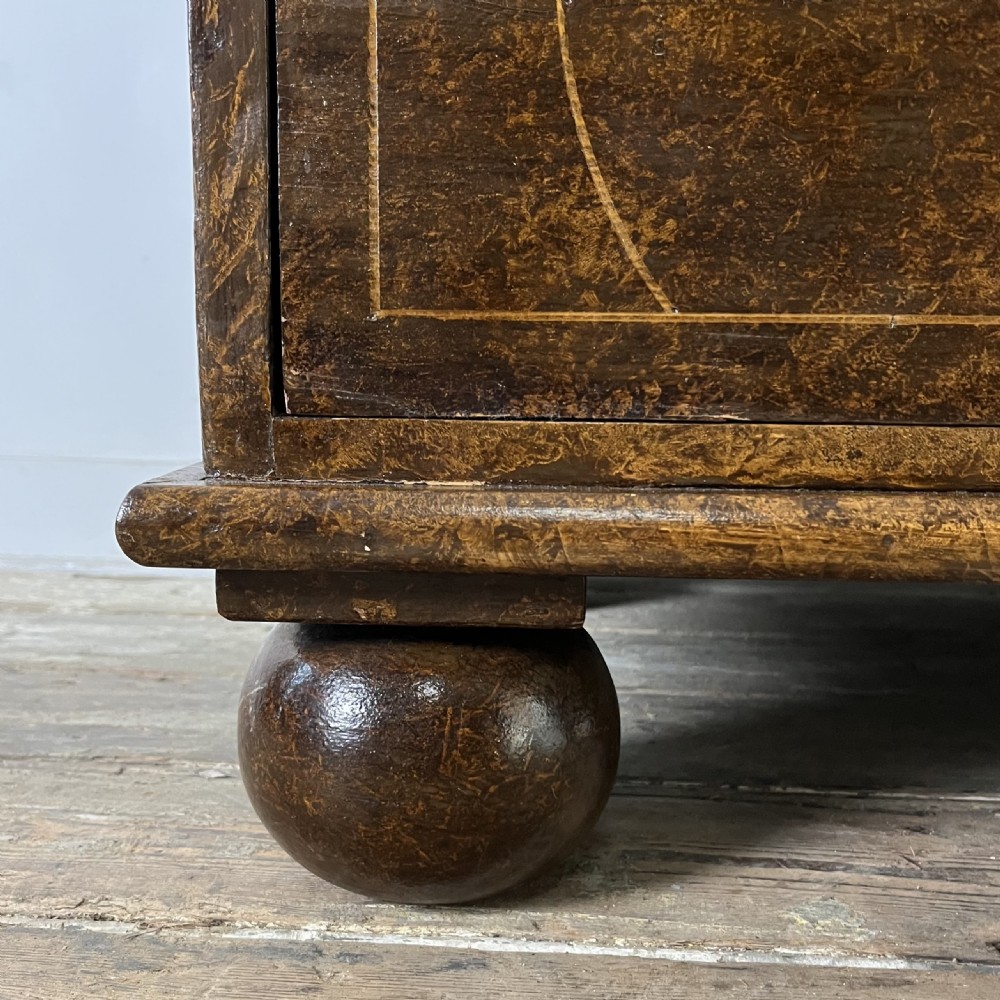 A nineteenth-century scumble-painted pine chest of drawers with decorative faux inlay lines, dark turned handles, and ball feet. View VI