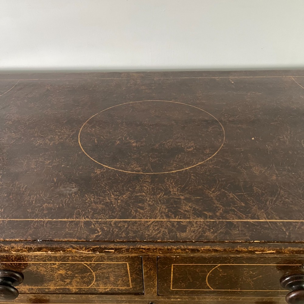 A nineteenth-century scumble-painted pine chest of drawers with decorative faux inlay lines, dark turned handles, and ball feet. View X
