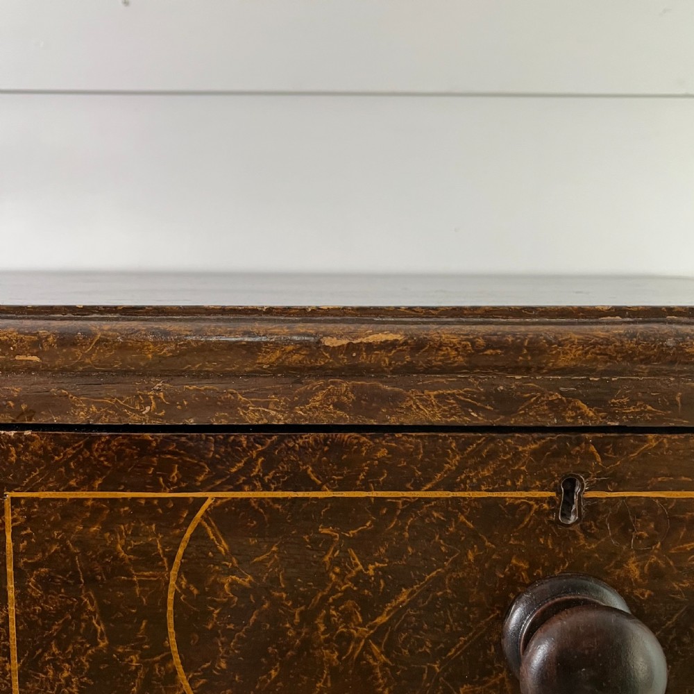 A nineteenth-century scumble-painted pine chest of drawers with decorative faux inlay lines, dark turned handles, and ball feet. View XII