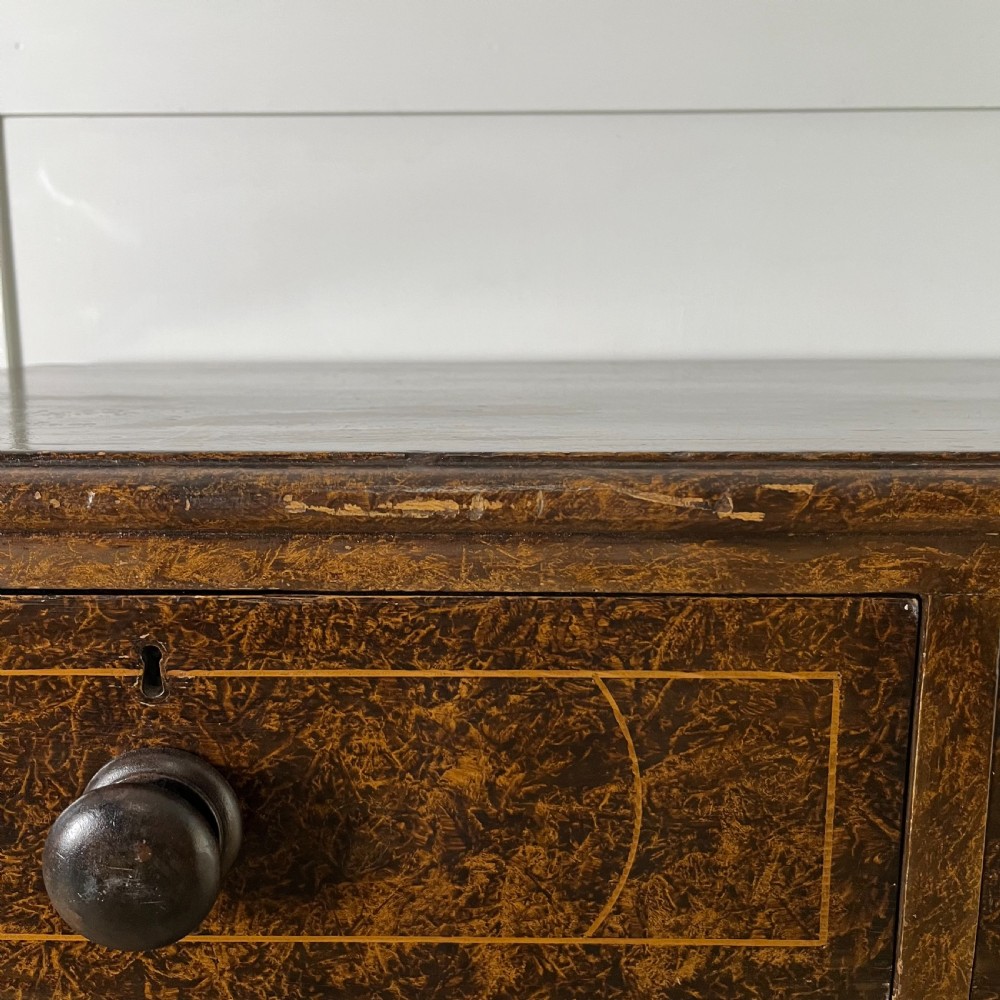 A nineteenth-century scumble-painted pine chest of drawers with decorative faux inlay lines, dark turned handles, and ball feet. View XIII