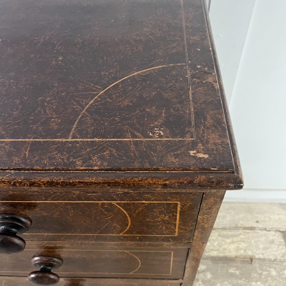 A nineteenth-century scumble-painted pine chest of drawers with decorative faux inlay lines, dark turned handles, and ball feet. View XIV