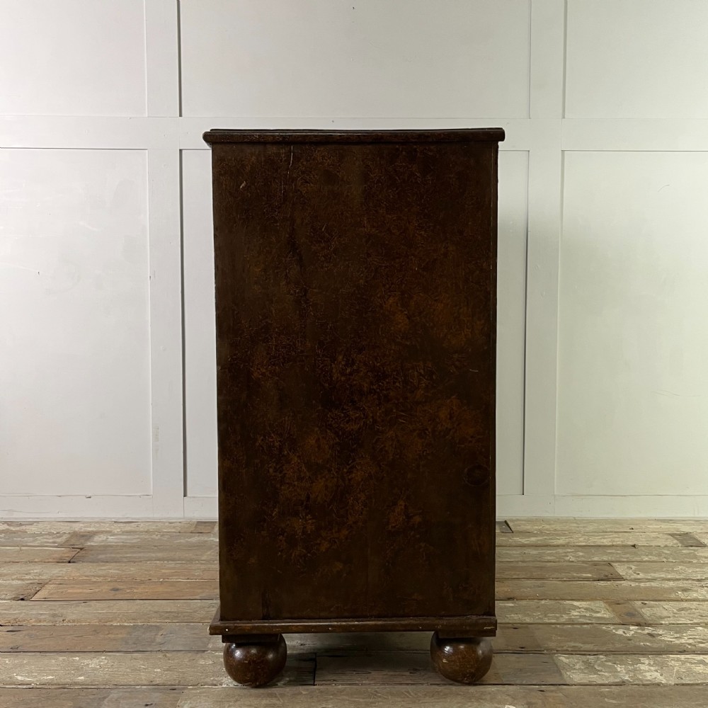 A nineteenth-century scumble-painted pine chest of drawers with decorative faux inlay lines, dark turned handles, and ball feet. View XVI